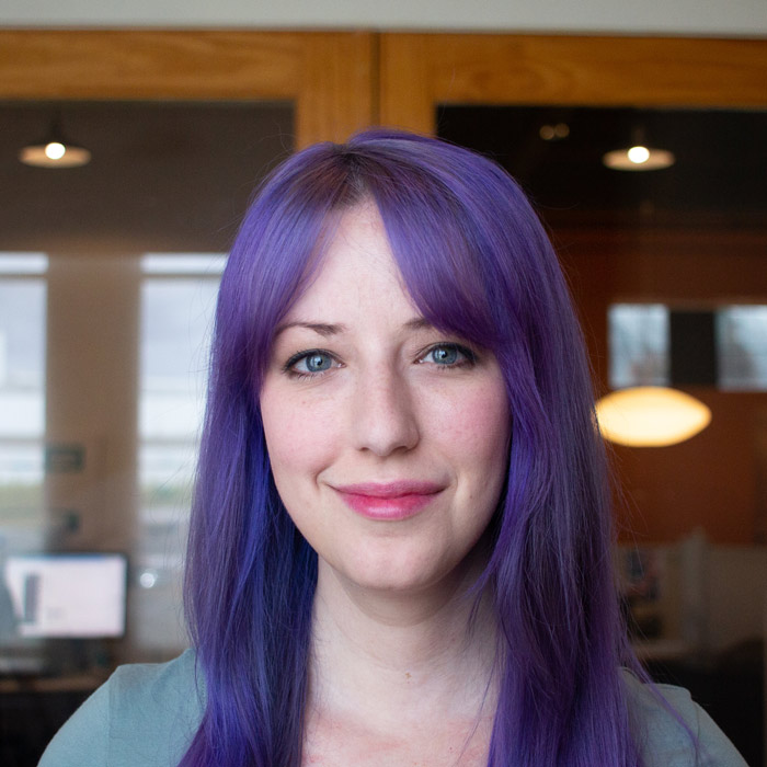 Headshot of Bekah in the truematter offices. She has purple hair.